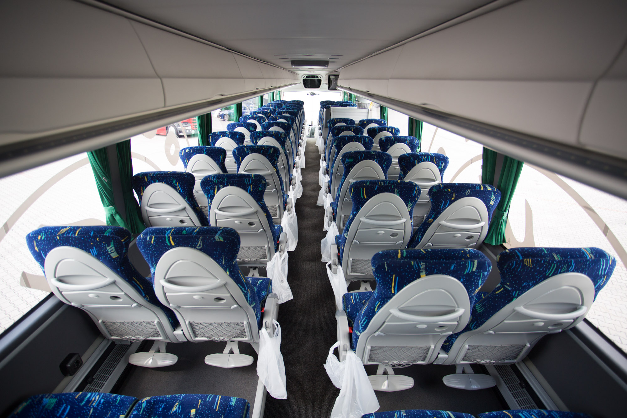 Interiér zájezdového autobusu – pohled do uličky mezi sedačkami